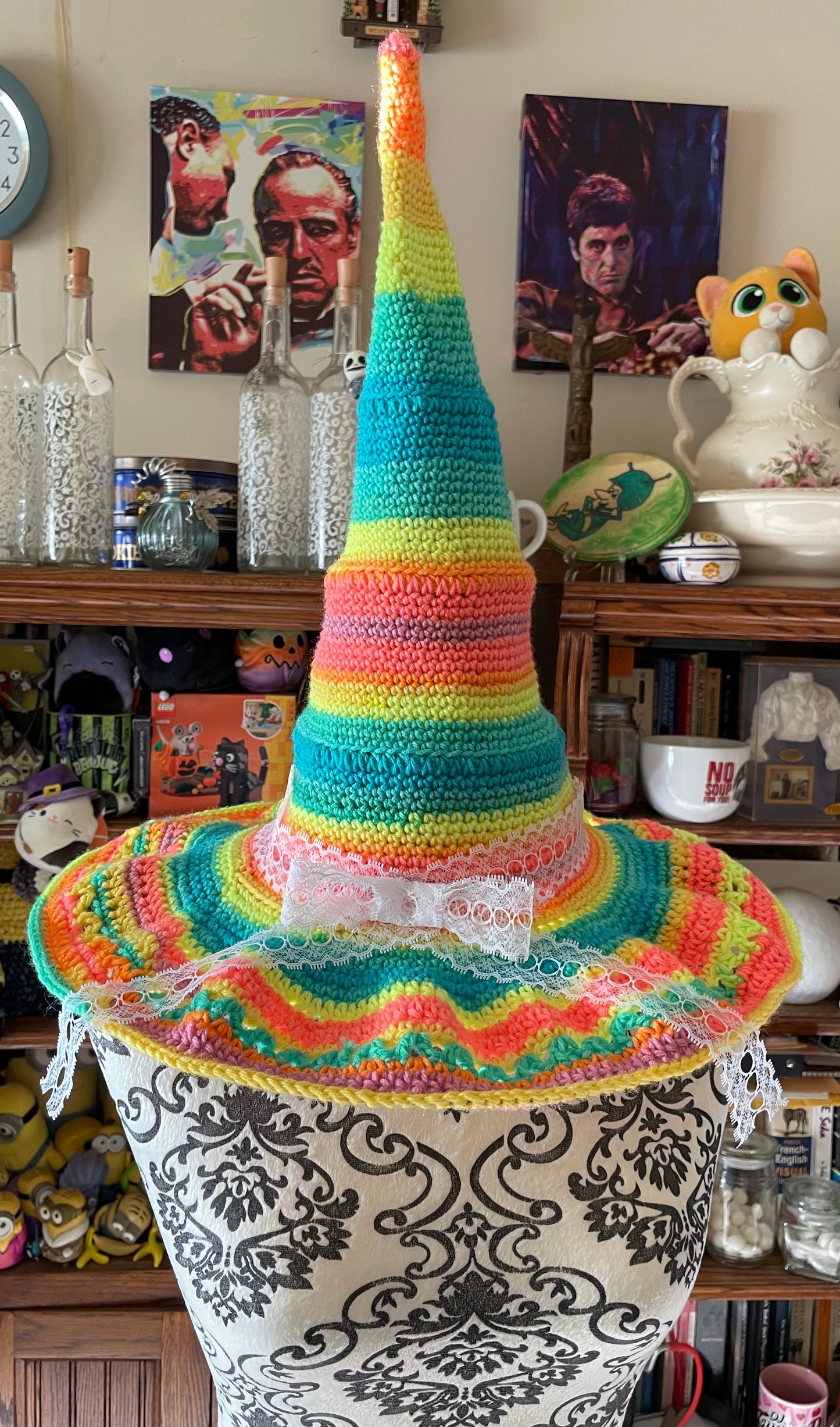 Colorful crocheted hat on a decorative stand with a bookshelf background