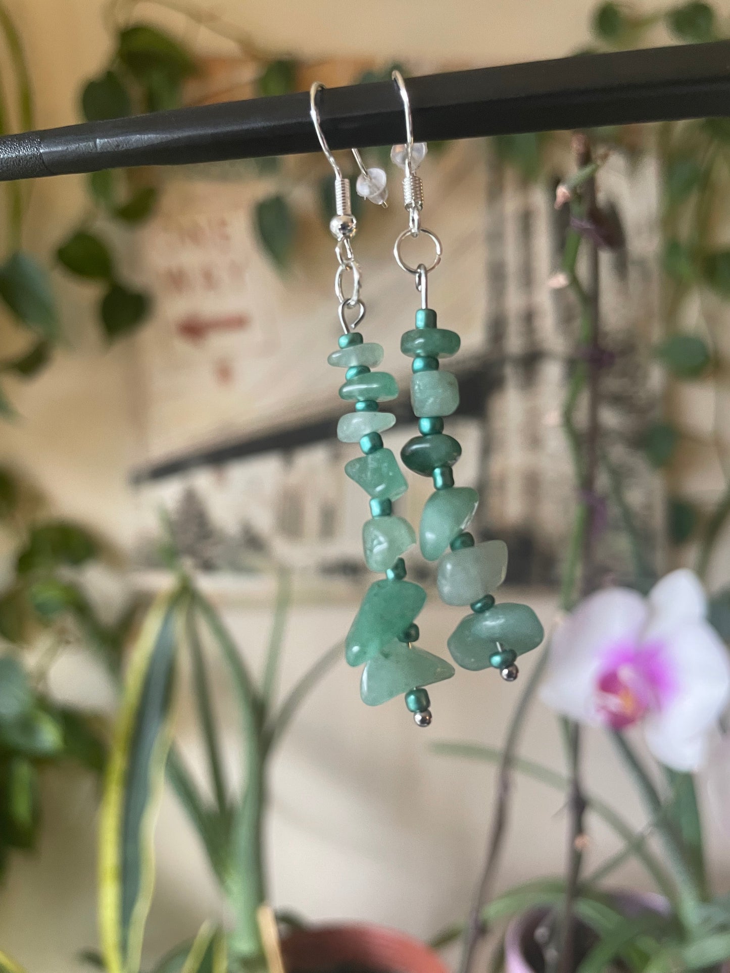 Green beaded earrings on a stand with a blurred background