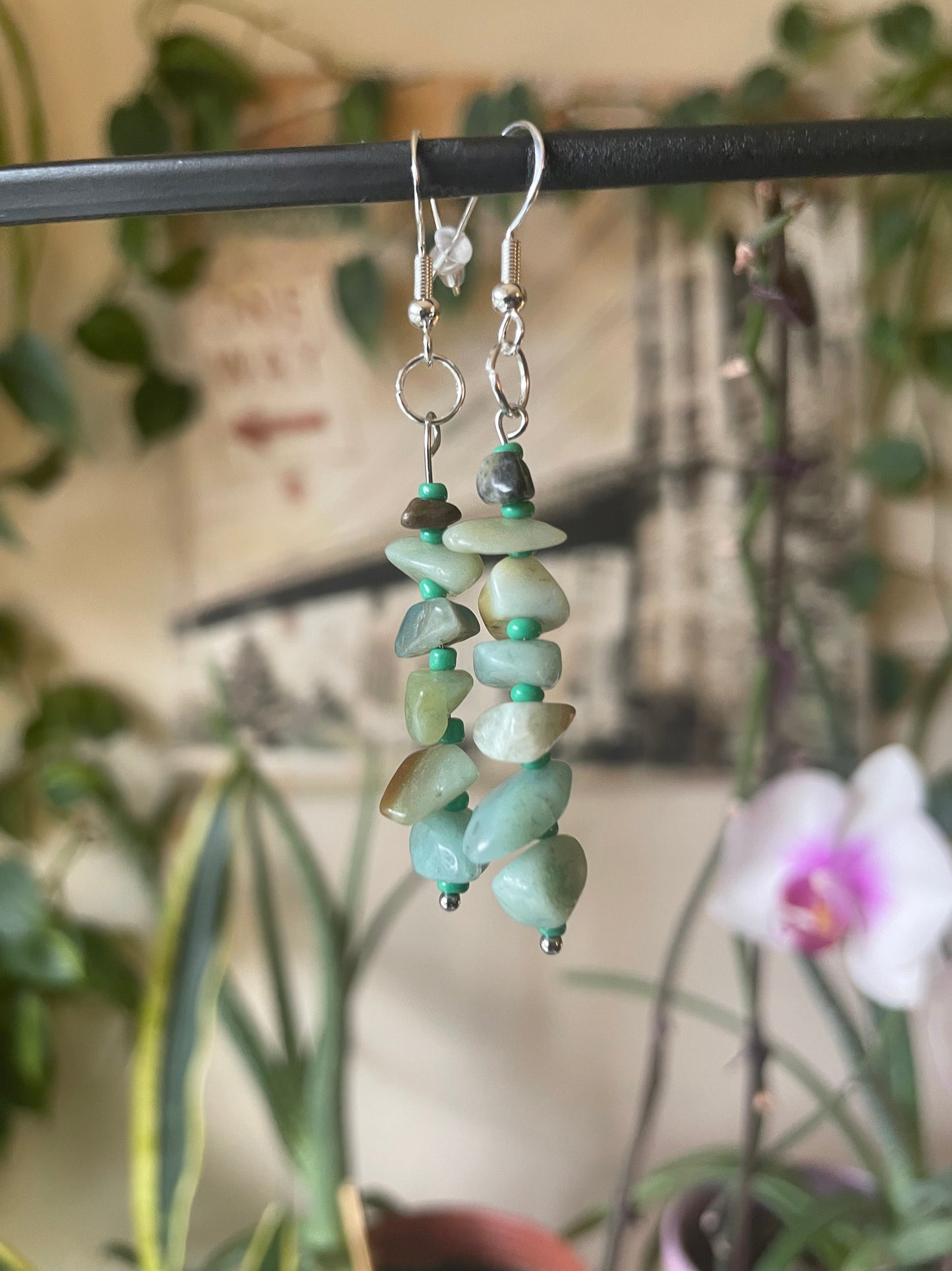 Green beaded earrings on a stand with a blurred background